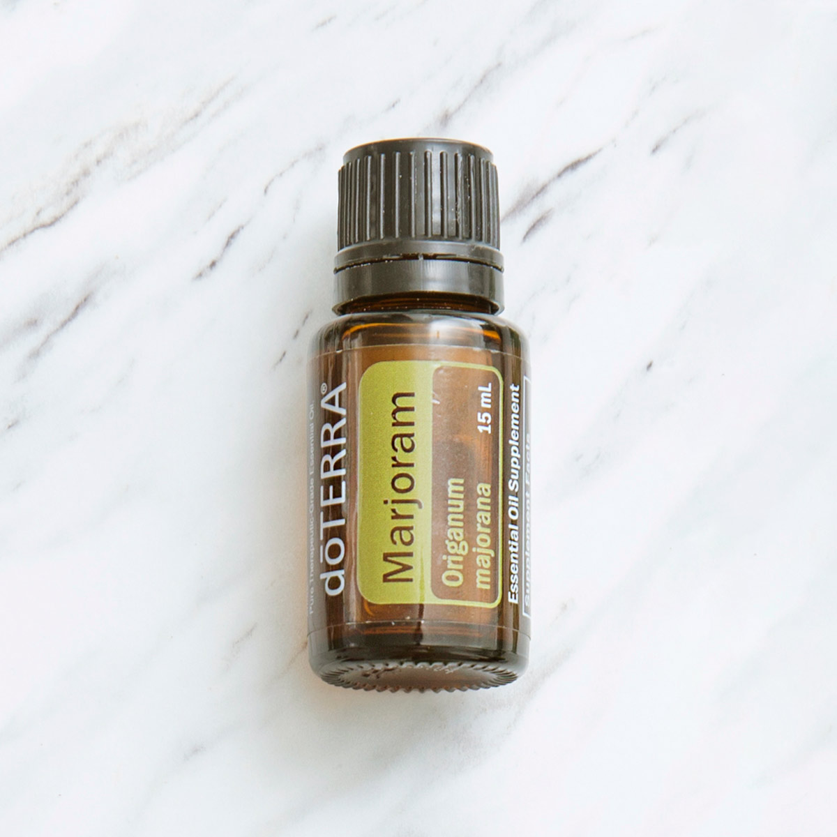doTERRA Marjoram oil bottle on granite surface. Marjoram oil has a wide variety of benefits, including internal benefits and benefits for massage. 